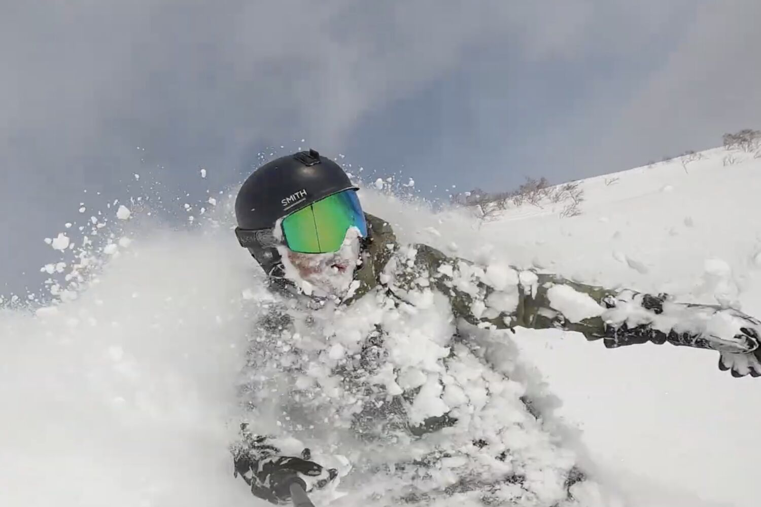 Snowboarder carving through deep powder with snow spraying, Japan backcountry