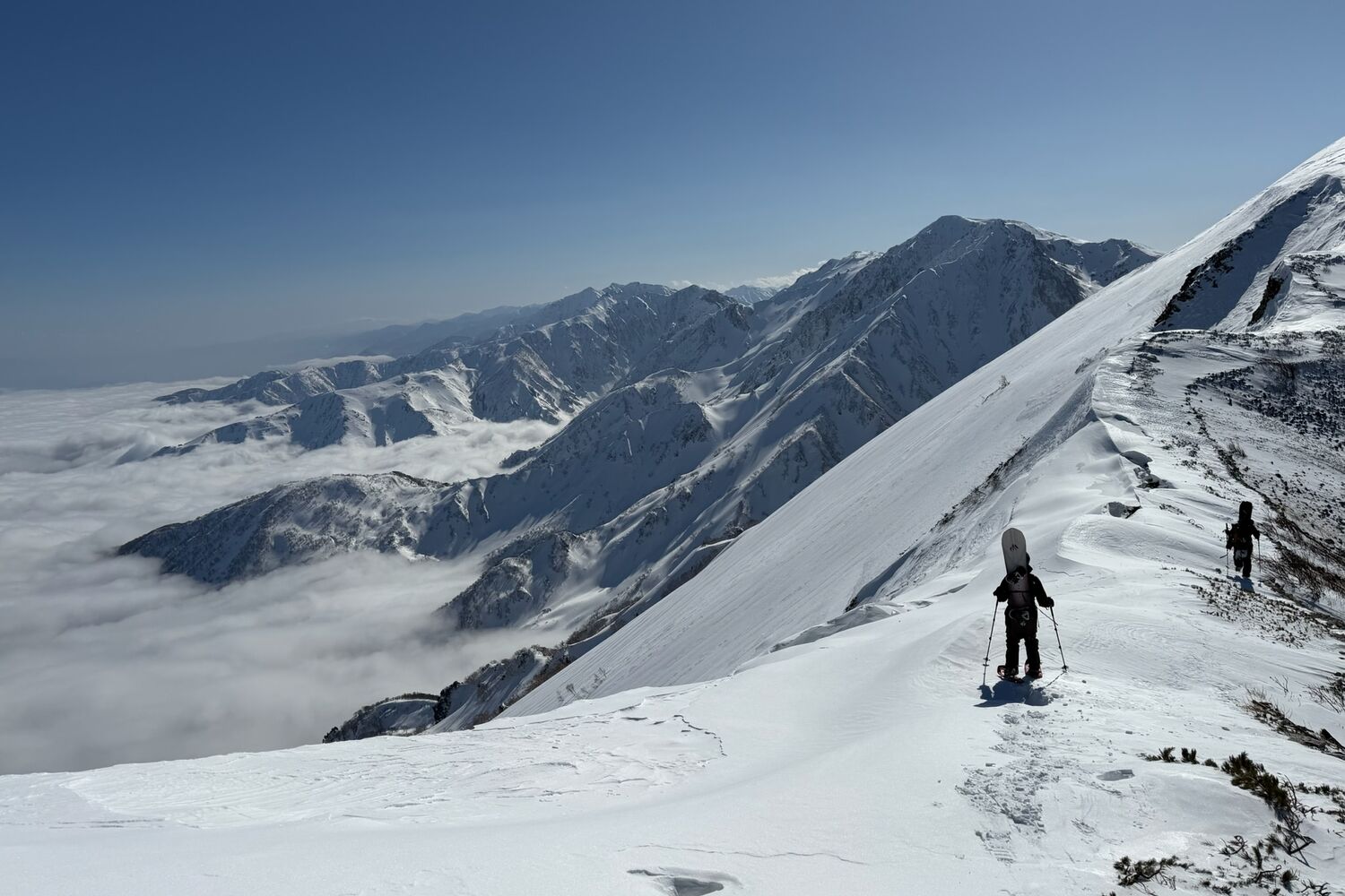 Splitboarders on a ridge above a sea of clouds in the Japan Alps