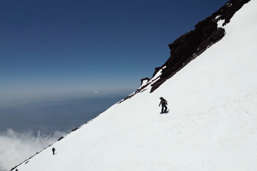 Snowboarding down the snow face of Mt Fuji above a sea of clouds