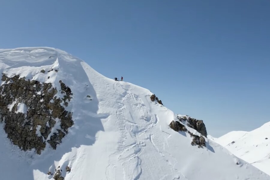 Drone view of the corniced summit of the Hakuba Sanzan with two riders on top